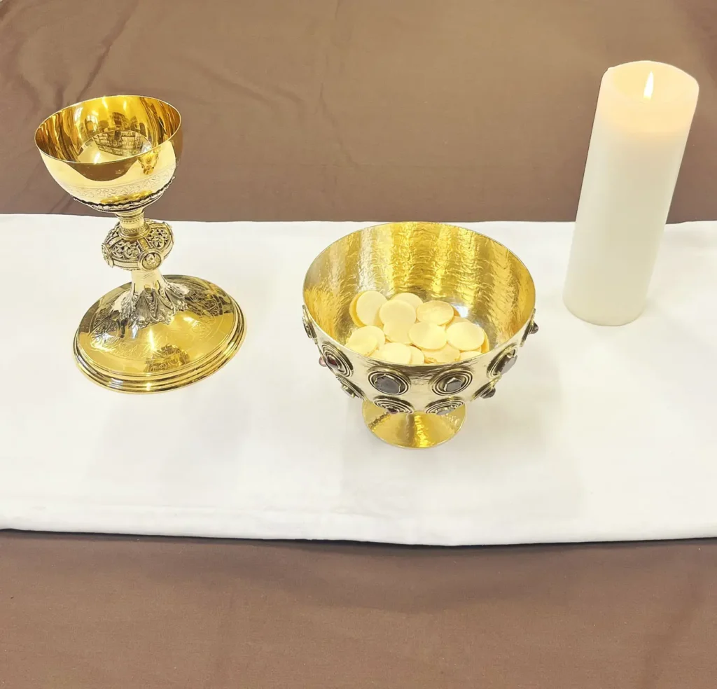 Foto von goldener Schale mit Hostien, Kelch und Kerze