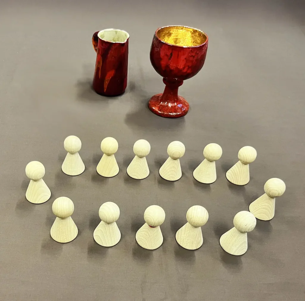 Foto eines Kelchs und Krugs, davor 13 Holzkegelfiguren