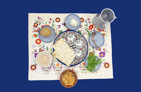Foto eines Sedertellers mit symbolischen Speisen und Becher.